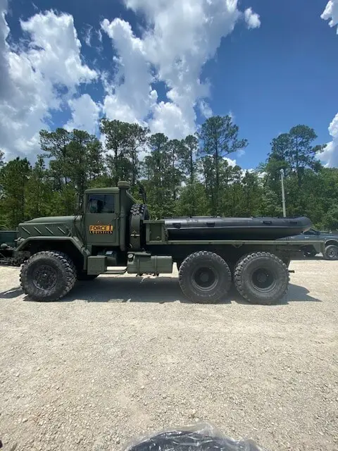 Six-wheel flatbed truck under pine trees