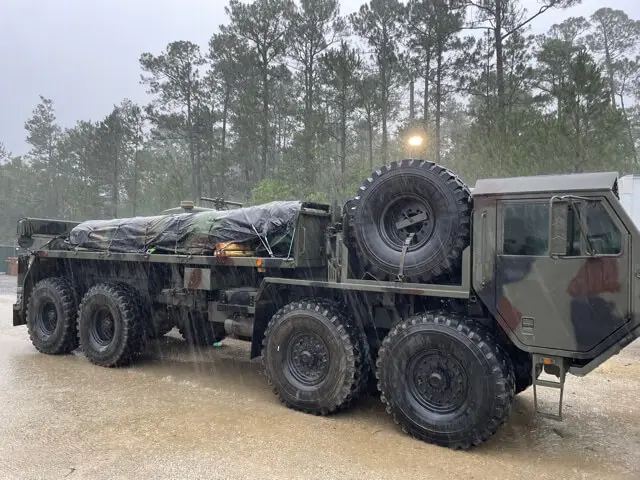 Eight-wheel camouflage truck with a covered load in the rain