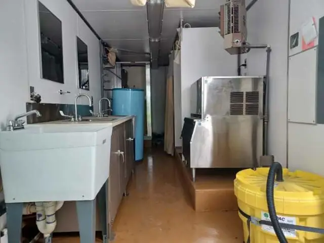 Utility room with sinks and an ice machine inside a support trailer